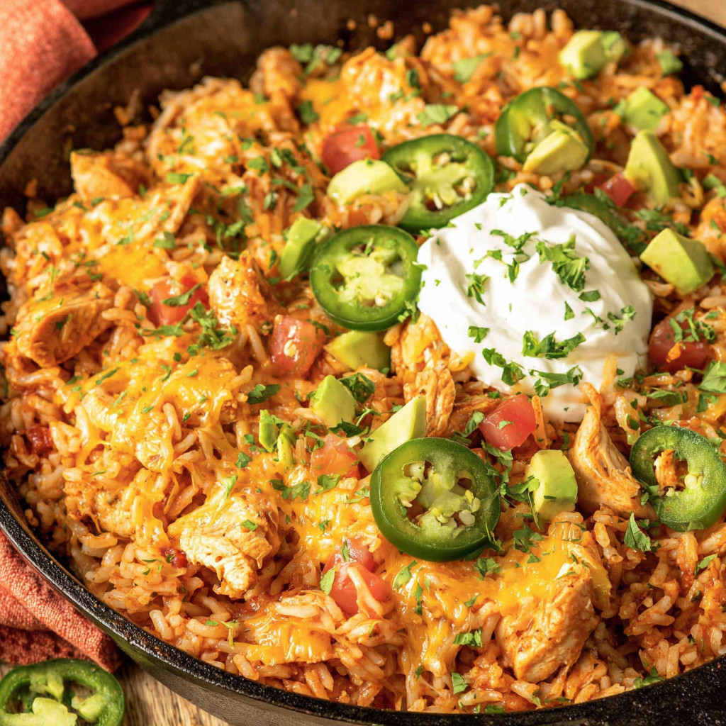 A bowl of rice with chicken, jalapenos, and cheese.