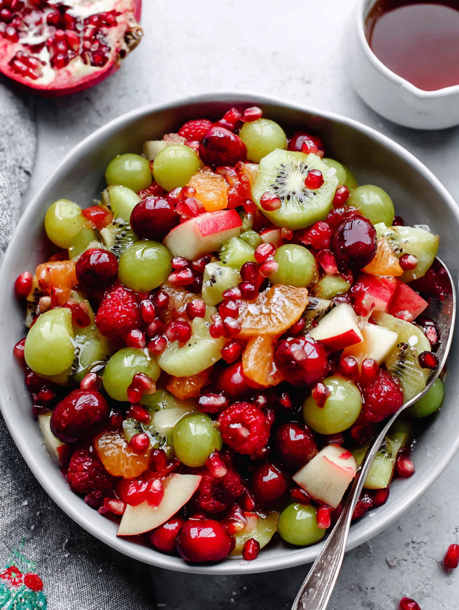 A bowl of fruit with kiwi grapes and pomegranate.