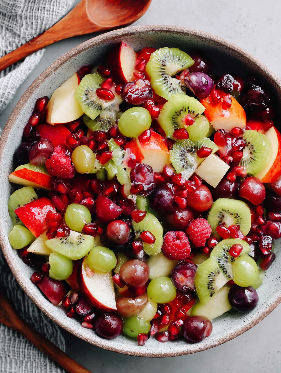 A bowl of fruit with kiwi grapes apples and berries.