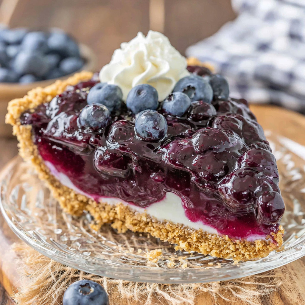 A slice of pie with blueberries and whipped cream.