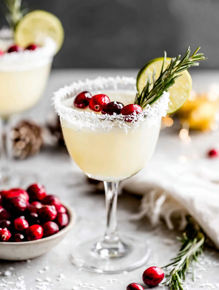 A glass of white wine with a cranberry and lime garnish.