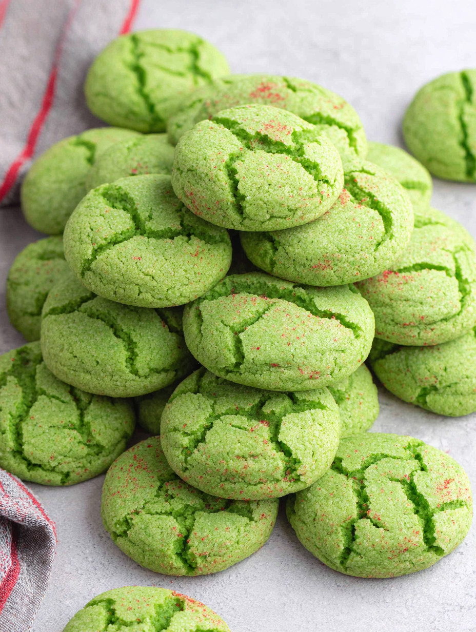 A stack of green cookies with red frosting.