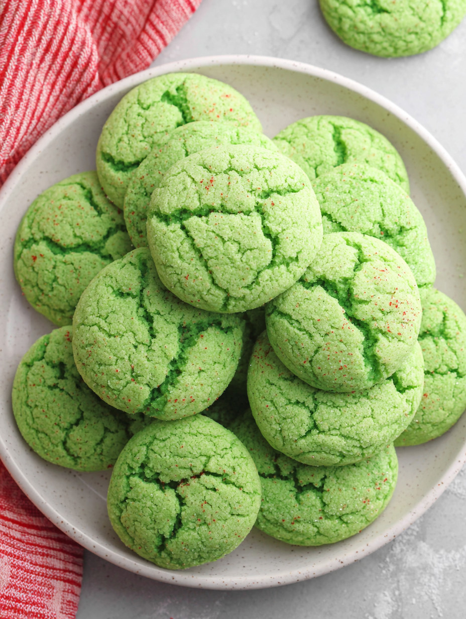 A plate of green cookies with red sprinkles.