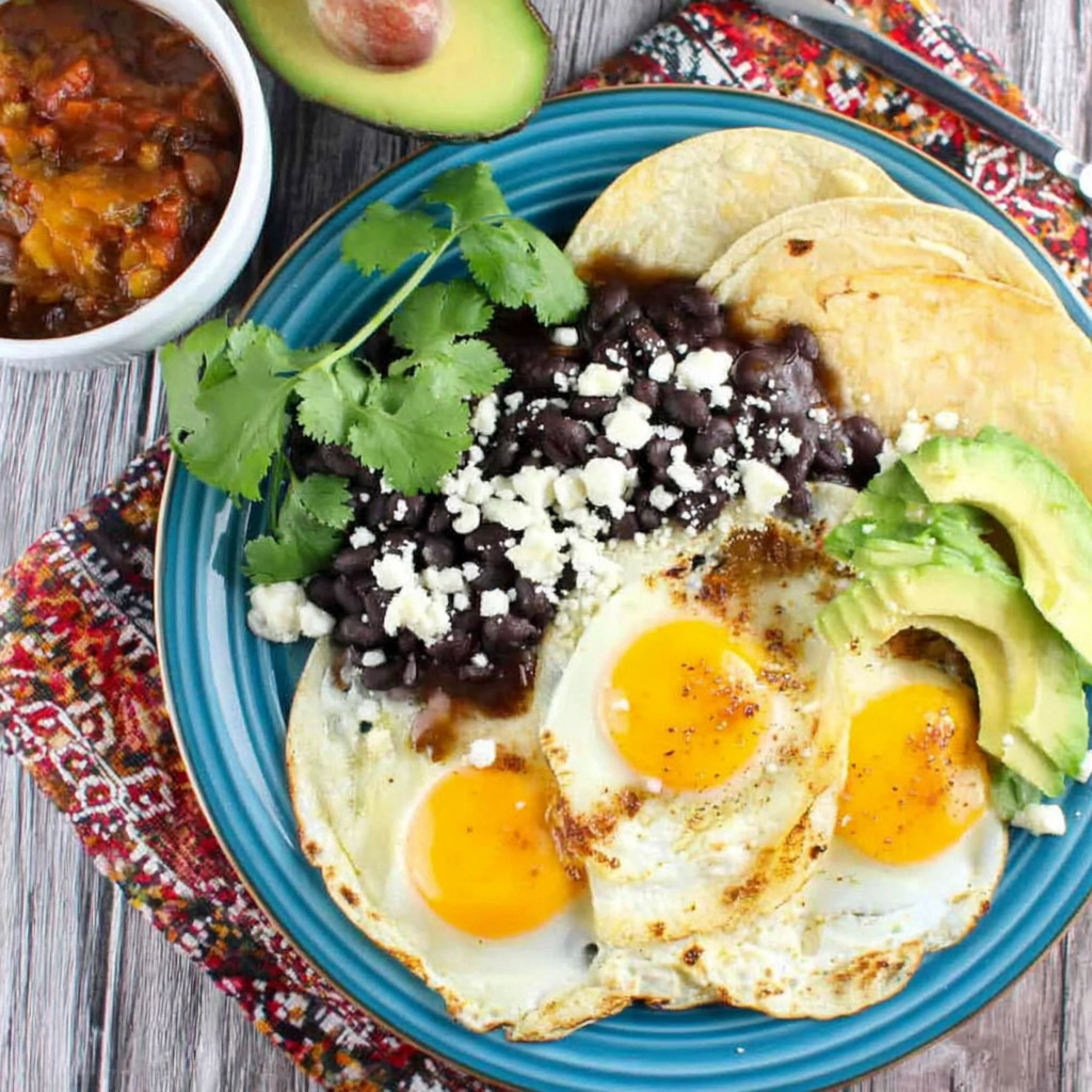 A plate of food with eggs, beans, and avocado.