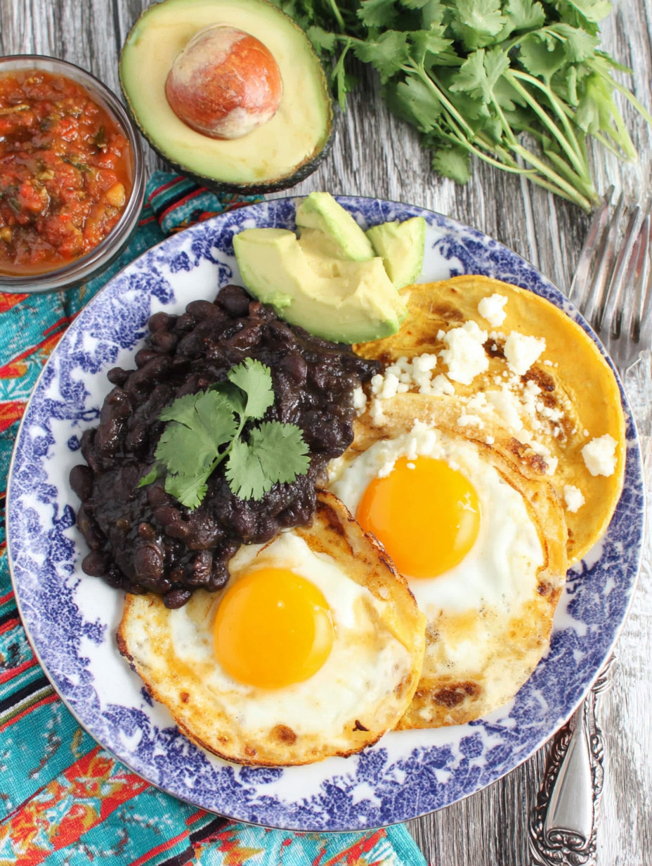 A plate of food with eggs, beans, and avocado.