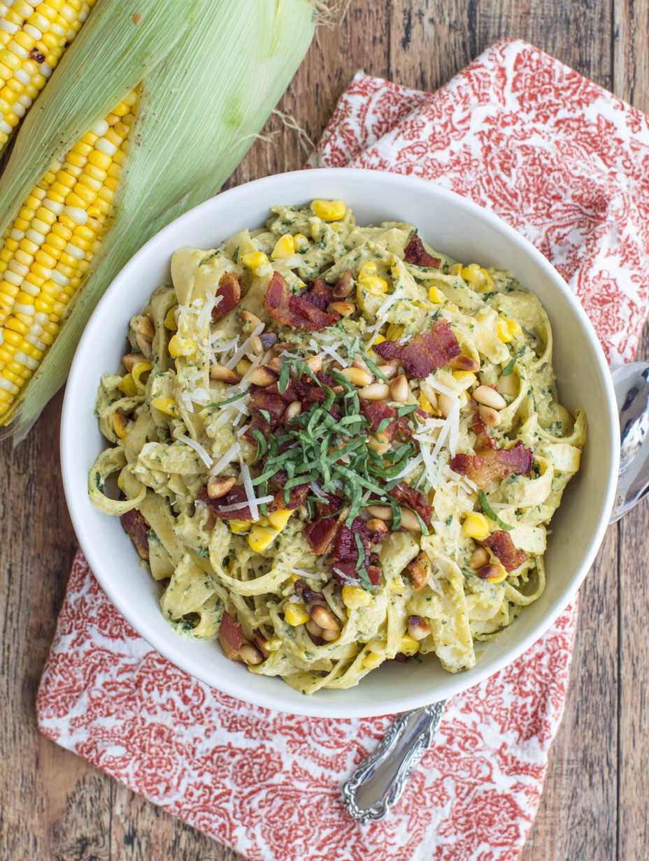 A bowl of pasta with bacon and corn.
