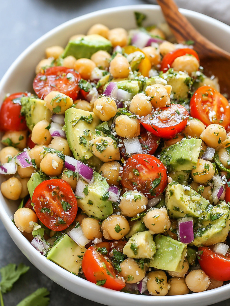 A bowl of chickpeas, tomatoes, onions, and avocado.