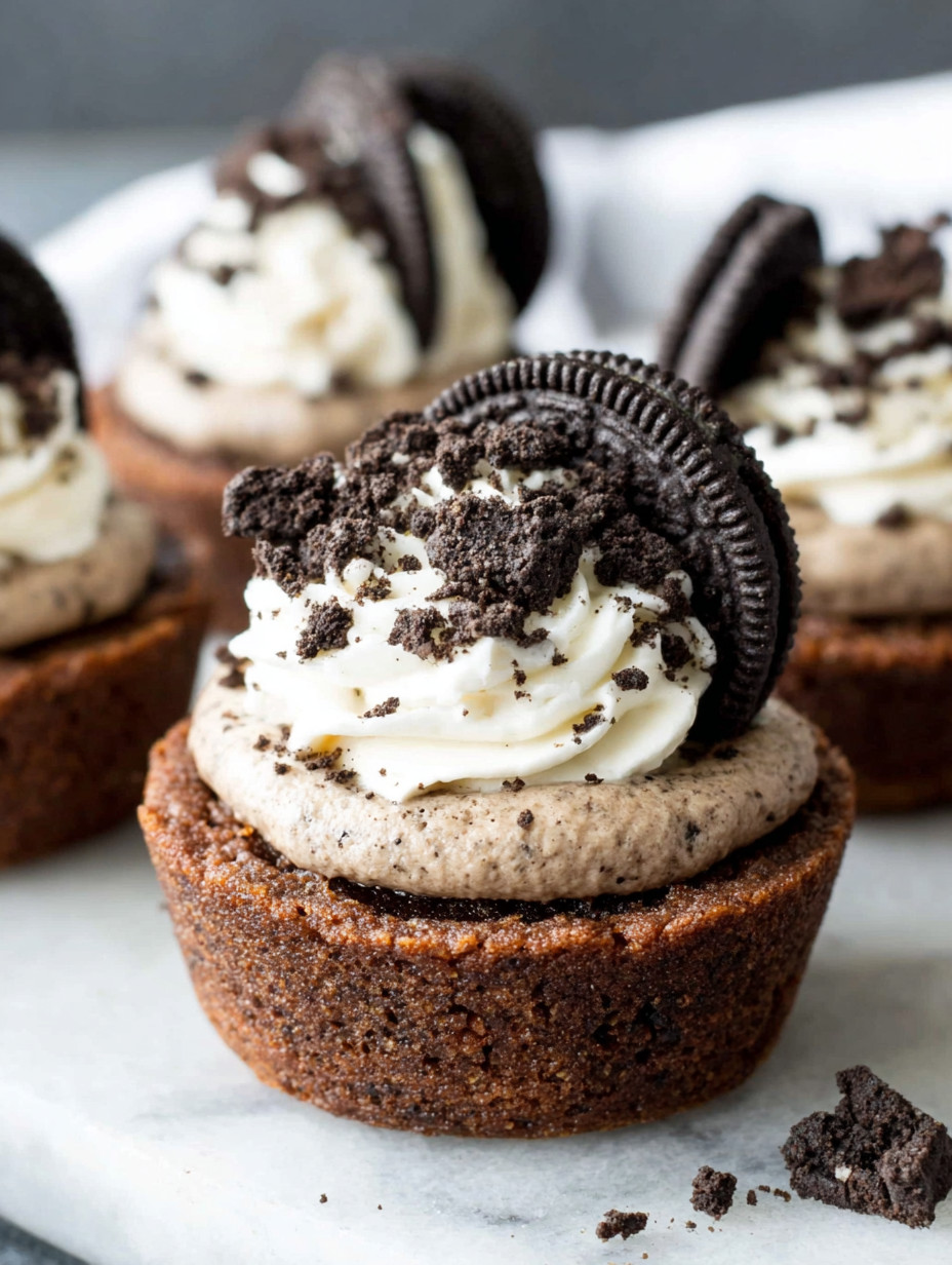 A cupcake with white frosting and a chocolate cookie on top.