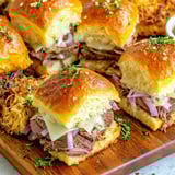 A wooden cutting board with a variety of sandwiches.