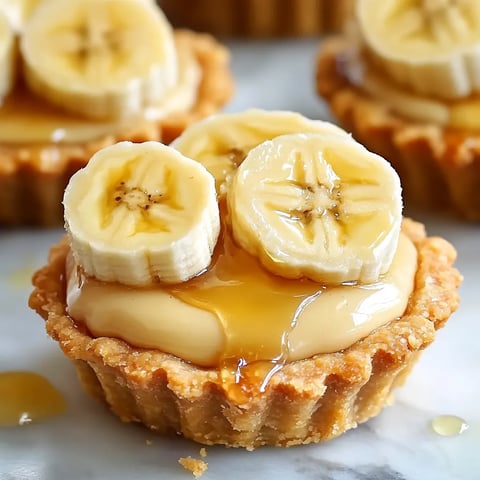 A close up of a banana cream pie with bananas on top.