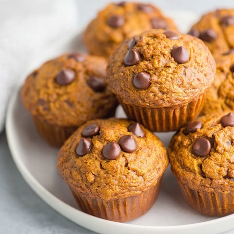 A plate of muffins with chocolate chips and pumpkin.