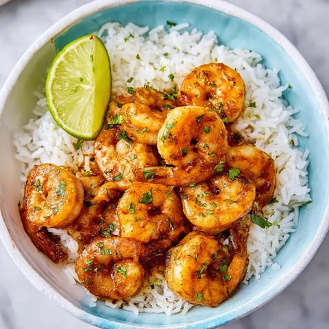 A bowl of shrimp and rice with a lime wedge on top.