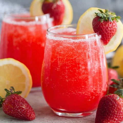 A glass of red drink with lemon slices and strawberries.