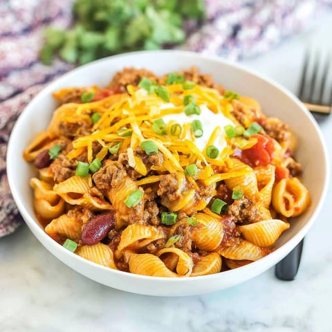 A bowl of chili with cheese and chives.