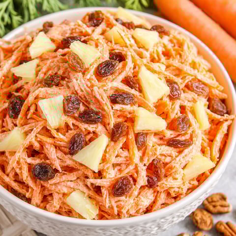 A bowl of food with raisins and carrots.