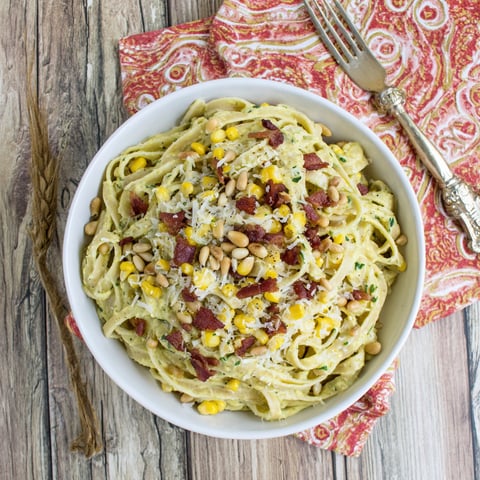 A bowl of pasta with corn and peanuts.