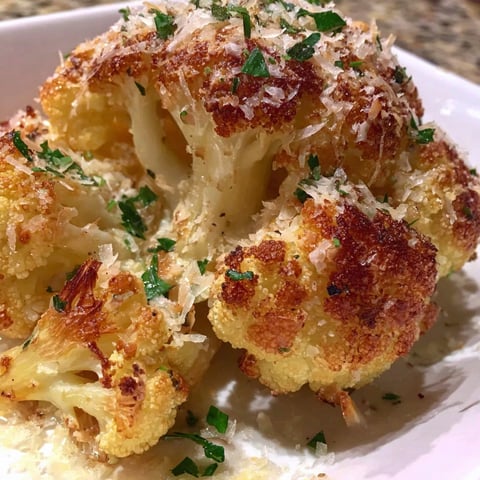 A plate of cooked cauliflower with cheese and herbs.